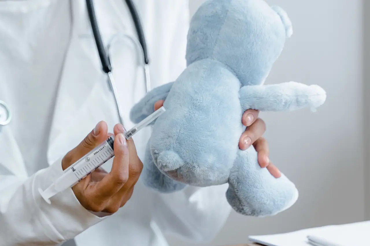 Person Holding Blue Plush Toy and White Syringe