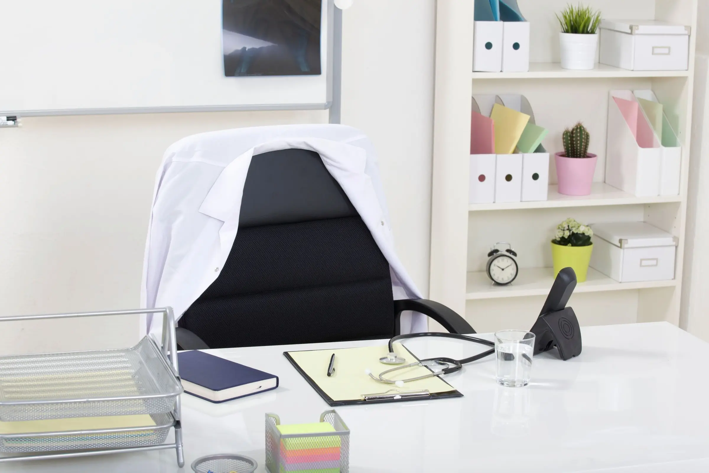 Doctor office table desk and black chair with stethoscope and white paper
